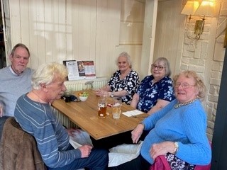 Image of people say around a table smiling at the camera