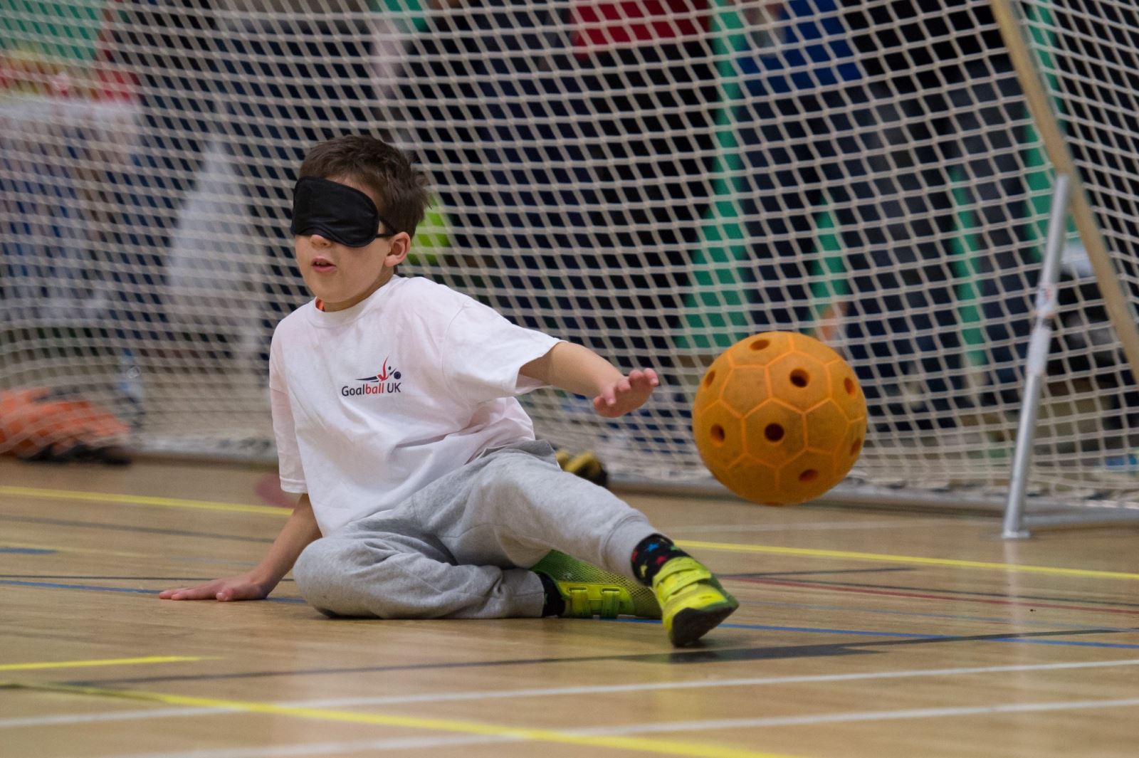 Child with eyeshades in front of goal as ball passes him
